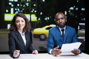 Diverse newscasters reading headlines in news studio, working in television industry to create exclusive content. Team of live journalists covering all important topics, entertainment segment. photo