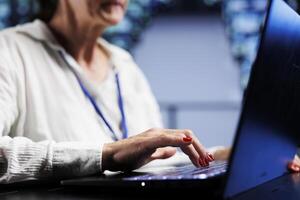 Precise serviceman using laptop, ensuring valuable data remains shielded from security menaces, safeguarding high tech facility servers against unauthorized access and vulnerabilities, close up photo