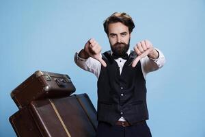 Valet at hotel gives thumbs down while appearing dissatisfied and unhappy on camera. Sophisticated bellhop symbolizes rejection and displeasure as negative emotions associated with disappointment. photo