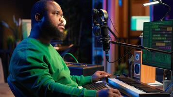 Skilled composer writing rhymes and lyrics to create new music in home studio, thinking about harmonic notes and verses to compose cool songs. Songwriter producing soundtracks with gear. Camera A. photo