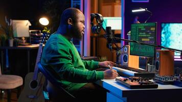 Songwriter taking notes to create new tracks for an album in his home studio, writing lyrics and harmonic elements before recording his song and editing on software, acoustical engineering. Camera A. photo