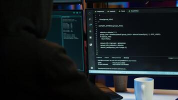 Cybercriminal coding, developing zero day exploit undetectable by antivirus software installed on systems, close up shot. Hooded developer building script able to trick firewalls, camera A photo
