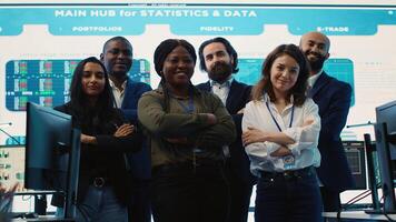 Diverse group of business professionals posing together in monitoring room, multinational company headquarters. Executive management team working with big data screen in the office. Camera A. photo