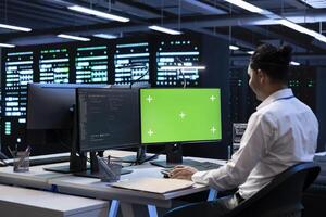 Programmer in data center using green screen computer to check for server performance issues. IT professional in server hub fixing errors slowing down hardware using mockup desktop PC photo