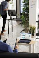Financial analyst analyzing stock exhange and investment revenue on laptop screen in corporate coworking space. Executive manager checking infographics and diagrams on computer in business office photo