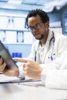 Diverse team of medics examining x ray results and healthcare data in a cabinet meeting, consulting the colleagues before putting a diagnostic. Physicians working together for healthcare recovery. photo