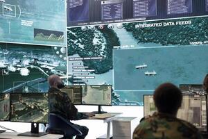 Army personnel monitoring surveillance imagery from satellite system on big screen in control room, collecting information for a new defense operation. Troopers working on reconnaissance. photo