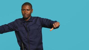 Portrait of joyous security guard doing thumbs up sign gesturing with finger while overseeing premises. Private law enforcement worker doing positive hand gesture, studio backdrop, camera A photo