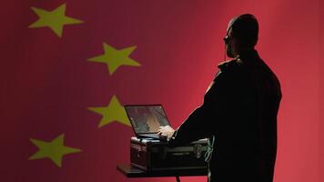 Chinese army military dispatcher looking at surveillance transmission on laptop, relaying informations for troops using headset, isolated over fluttering China flag background, camera A photo