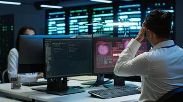 Engineer in server hub frightened by hacker passing company firewall and stealing sensitive user data. Afraid man panicks after seeing security breach notification on computer in data center, camera A photo