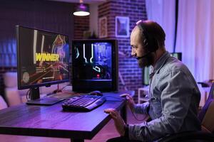 Gamer winning intense singleplayer spaceship arcade racing videogame on powerful gaming computer setup with rgb lights. Man feeling relieved after finally passing hard game mission photo