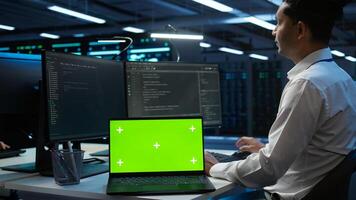 Admin in data center using isolated screen laptop to design, implement and manage gear, ensuring optimal performance and reliability. Expert in server room coding on chroma key notebook, camera B photo
