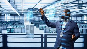Engineer using augmented reality tech in data center, installing software, troubleshooting issues. African american expert in server hub looks at AR hologram, establishing performance benchmarks photo