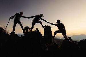 Silhouette of a group of climbers on a mountaintop. Success, teamwork and unity. photo