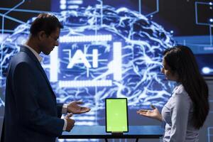 Technician running AI cognitive computing technology on mockup tablet to simulate computerized model. Green screen digital device used by IT employees to do data mining with artificial intelligence photo