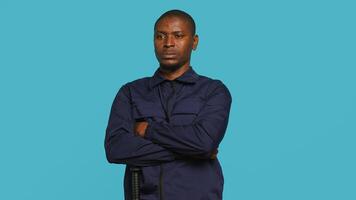 Security guard does surveillance for various organizations and venues, ensuring protection of property and personnel, studio background. Portrait of intimidating man in uniform crossing arms, camera A photo