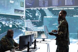 Military control room features army personnel monitoring surveillance systems, soldiers integrating data and coordinating strategic missions. Support decision making and efficiency. photo