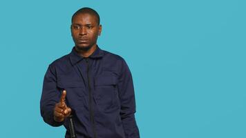 Portrait of security guard doing shush sign gesturing with finger to intruder while overseeing premises. Private law enforcement worker urging people to keep quiet, studio backdrop, camera A photo