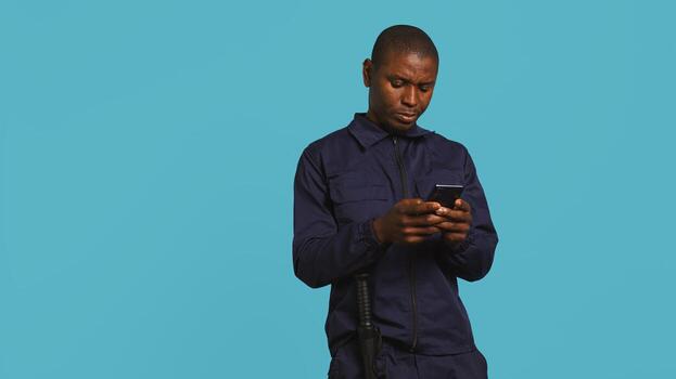 Security guard using smartphone, taking break during protection job shift. Portrait of bodyguard texting friends at work using mobile phone, isolated over studio background, camera B photo