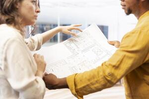 Salesman guiding female entrepreneur on a modern office space tour, evaluating real estate layout and blueprints. Businesswoman negotiating renting deals for startup relocation. photo