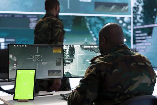 Army IT expert in control center collecting real time battlefield data, process satellite surveillance imagery for successful military defense mission. Using green screen isolated display. photo
