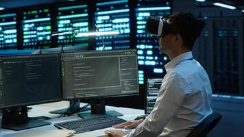 Data center admin responsible for installation of networking systems wearing high tech VR headset. IT worker doing maintenance on server farm gear using virtual reality technology, camera A photo
