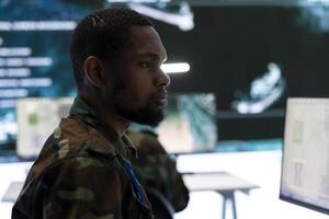 Military personnel in a high tech command center monitor satellite feeds, process and coordinate intelligence operations. Maintaining national security and supporting strategic army missions. photo
