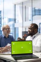 Senior couple exploring various pension plans next to green screen with financial advisor in modern office. Broker expert discussing with old people about their life savings. photo
