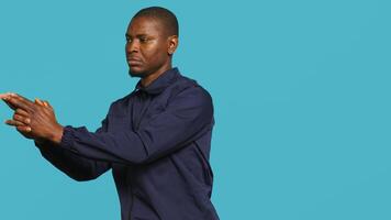 Portrait of security job employee shooting gun, detaining perpetrators while following legal protocols. Patrol guard follows conduct codes, doing pistol fingers gesturing, studio background, camera A photo