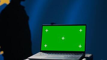 European Union agency using green screen laptop to protect against mass propaganda affecting elections. EU security service engaging in psychological operations using mockup device, close up, camera A photo