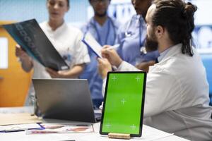 Licensed doctor and his staff review x ray scan results next to isolated copy space screen, examining hospital records before putting a diagnosis. Consulting analytics and radiography. photo