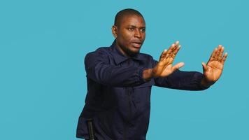 Portrait of security guard pushing back intruders while overseeing premises. Private law enforcement worker shoving away trespassers with hands, studio backdrop, camera A photo