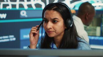 Indian woman dispatch operator gives directions to couriers, avoiding traffic by monitoring radar CCTV surveillance footage. Employee uses gps coordinates and satellite map. Camera A. photo