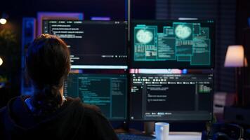 Dangerous hacker writing lines of code on PC from secret apartment, trying to get past security systems. Evil software developer building scripts that can hack devices, camera B photo