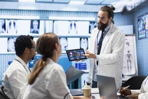 In a treatment center, healthcare professionals review mri scan test results and neurology x rays. Medics with neuroscience expertise ensuring development of treatment options, teamwork. photo