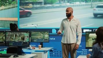 Team leader assigning tasks to his employees in a monitoring room, working on tracking surveillance footage on CCTV security system cameras. People gather public intelligence. Camera A. photo
