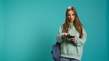 Euphoric woman playing intense gaming console game, celebrating win, studio background. Ecstatic young girl using controller, excited after being victorious in videogame, camera B photo