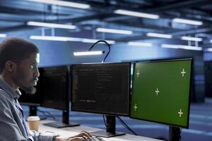 Engineer working on green screen PC in data center housing thousands of servers, storage devices, and networking components, providing vast amounts of computing resources photo