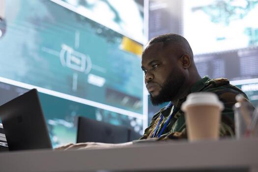 Secret service expert in an advanced command post manages reconnaissance and intelligence gathering activity, interprets real time data. IT analyst in base of operations with big screen. photo