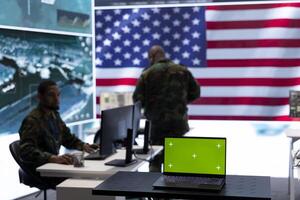 American army working in a command post with green screen, soldiers examining satellite imagery for clues regarding a national safety operation. US military control tower for surveillance. photo