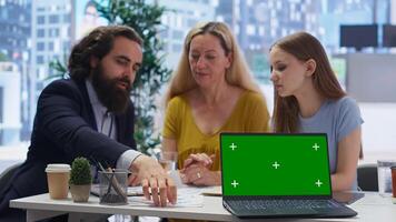 Financial advisor showing data graphs on green screen notebook to customers, analyzing market trends to do forecasting. Clients checking investment plan on chroma key laptop, camera B photo