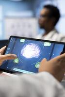 Inside a treatment center, doctor analyze mri brain scan data on a tablet, examining tomography results. Neurology experts team focus on x ray scans and diagnostics for disease prevention. Close up. photo