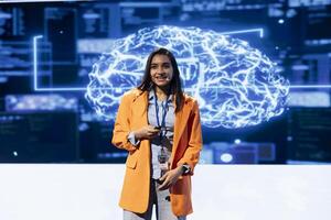 Smiling presenter talking at AI summit using mic, sharing industry expertise to inspire audience. Technician exploring latest artificial intelligence products and services at tech event photo