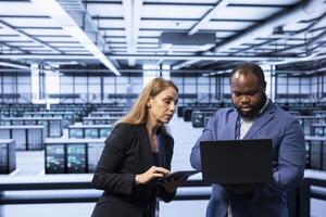 Team of programmers in data center checking rigs and hardware, doing checkup. Teamworking colleagues planning and executing high tech server hub facility migrations and upgrades photo
