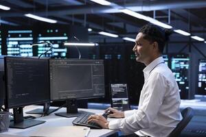 System administrator troubleshooting hardware and software errors in server farm. IT staff member maintaining mainframes network infrastructure in data center, coding on PC photo