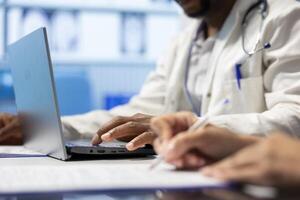 Skilled doctor writing down options and plans for recovery treatment, consulting with his colleagues in a meeting after seeing x ray test results. Examining records and scans for diagnosis. Close up. photo