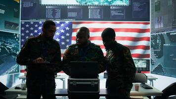 Military officer in a high tech control center engages in cybersecurity operations, protecting classified data from threats and managing digital warfare strategies to maintain state secrets. Camera B. photo
