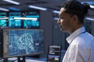 Programmer working on computer in data center with artificial intelligence technology to process massive datasets, close up. Indian employee in server hub storing data used for deep learning photo
