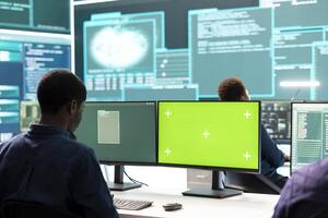 Governmental hackers working on computer with green screen to protect data and network security. Focusing on cyber defense, malware detection to prevent cyber attacks and espionage. photo