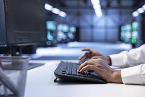 Programmer typing on keyboard, optimizing data center performance and capacity using computer. Close up of IT expert troubleshooting mainframes to ensure optimal performance and minimize downtime photo